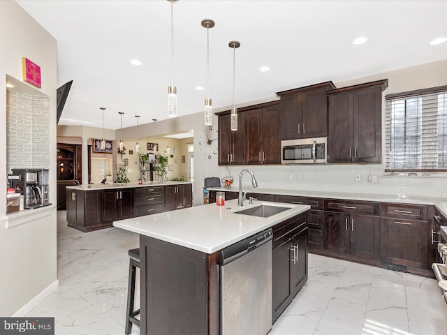 kitchen with tasteful backsplash, a center island with sink, marble finish floor, stainless steel appliances, and a sink