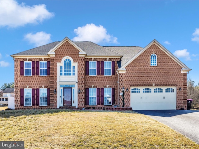 view of front of house featuring aphalt driveway, brick siding, and a front yard