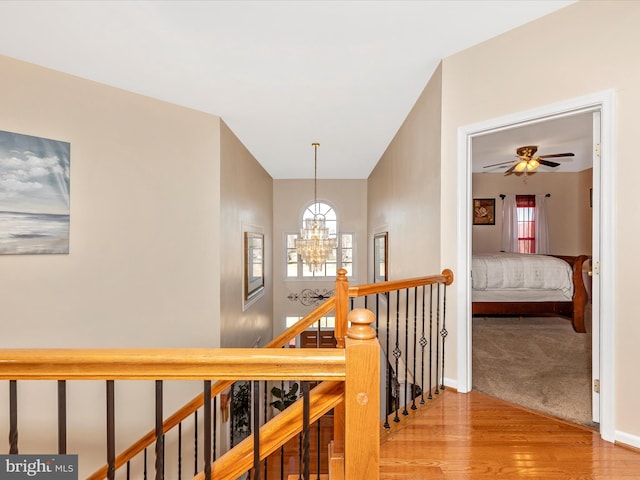 hallway with an upstairs landing, a notable chandelier, baseboards, and light wood-style floors