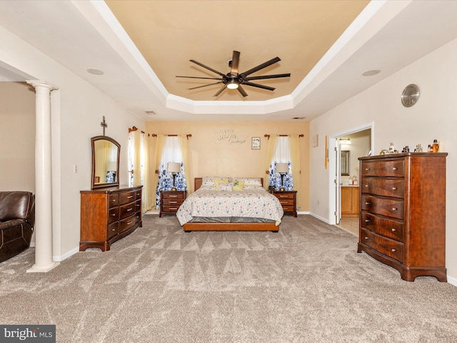 bedroom featuring a tray ceiling, decorative columns, carpet, and baseboards