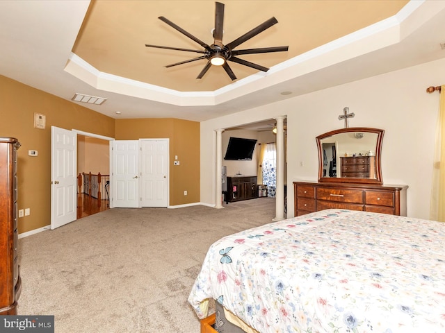 carpeted bedroom featuring a raised ceiling, baseboards, visible vents, and ornamental molding