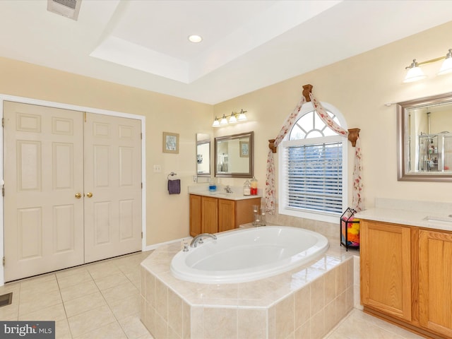 bathroom with a garden tub, a tray ceiling, visible vents, and tile patterned floors