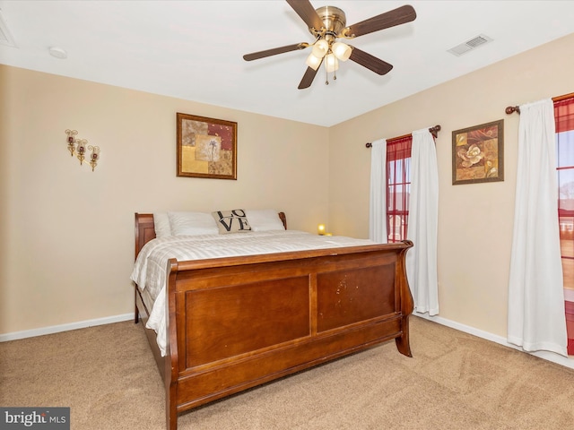 bedroom featuring visible vents, light colored carpet, baseboards, and ceiling fan