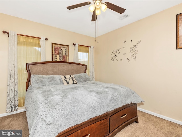 bedroom featuring visible vents, baseboards, light colored carpet, and a ceiling fan