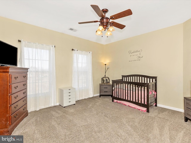 bedroom featuring a nursery area, visible vents, baseboards, and carpet