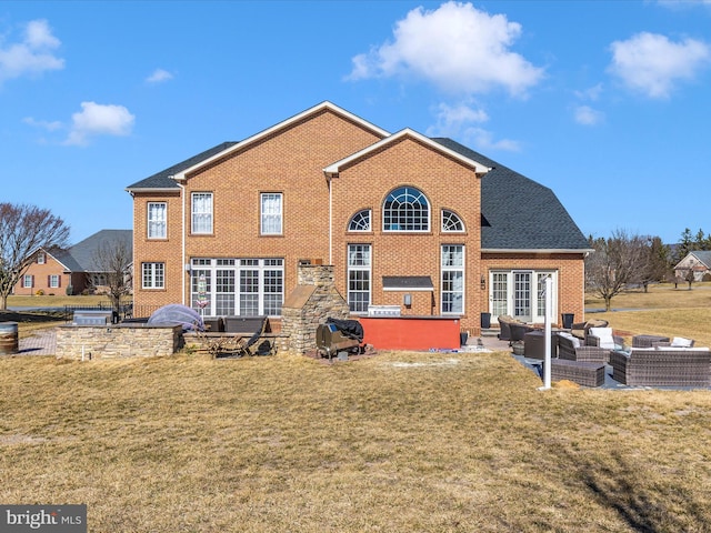 back of property featuring an outdoor living space, a lawn, brick siding, and a patio