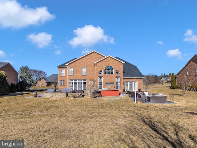 rear view of house featuring a yard, brick siding, outdoor lounge area, and a patio area