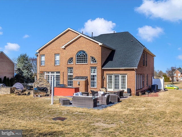 back of property featuring a yard, a patio area, brick siding, and an outdoor hangout area