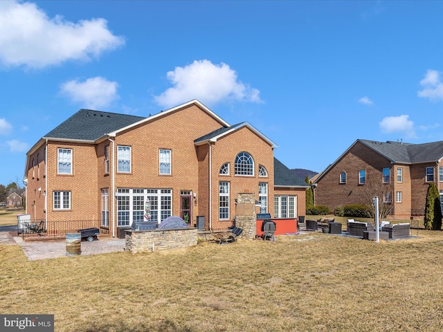 back of house with an outdoor living space, a yard, a patio, and brick siding