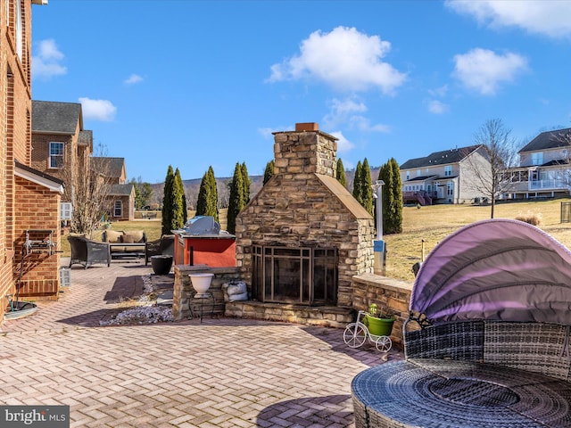 view of patio with a residential view and an outdoor stone fireplace