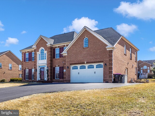 view of front facade with aphalt driveway, a front yard, brick siding, and an attached garage