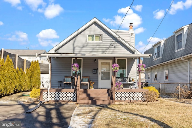 view of front of property featuring a porch, fence, and a front lawn