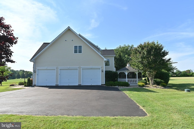 view of side of home featuring a gazebo, a yard, an attached garage, and aphalt driveway