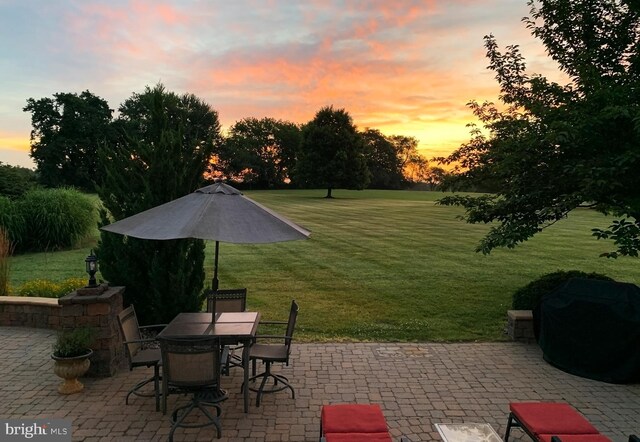 patio terrace at dusk with a lawn and outdoor dining area