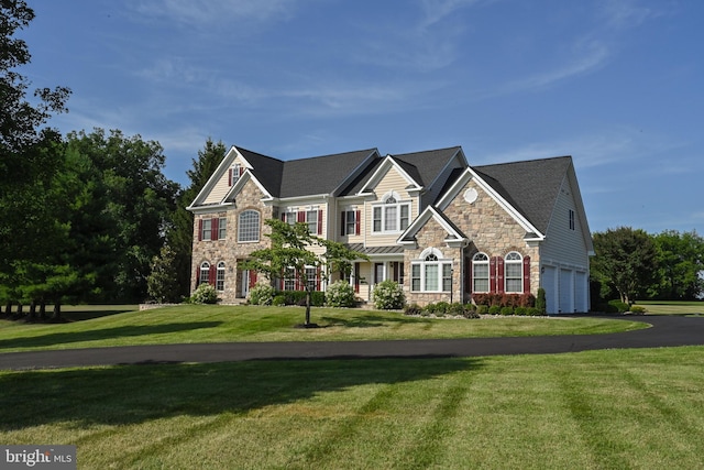 view of front facade with a garage, driveway, stone siding, and a front yard