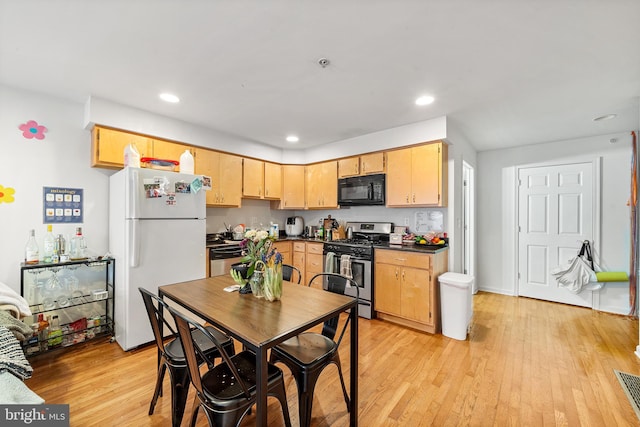 kitchen featuring light wood finished floors, recessed lighting, dark countertops, light brown cabinetry, and appliances with stainless steel finishes