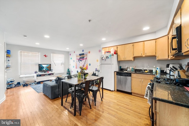 kitchen featuring black microwave, light wood-style floors, stainless steel dishwasher, freestanding refrigerator, and gas stove