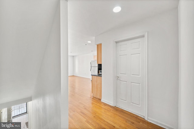 hall featuring baseboards, light wood-style flooring, and recessed lighting