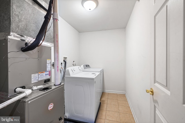 clothes washing area with light tile patterned floors, laundry area, baseboards, and washer and dryer