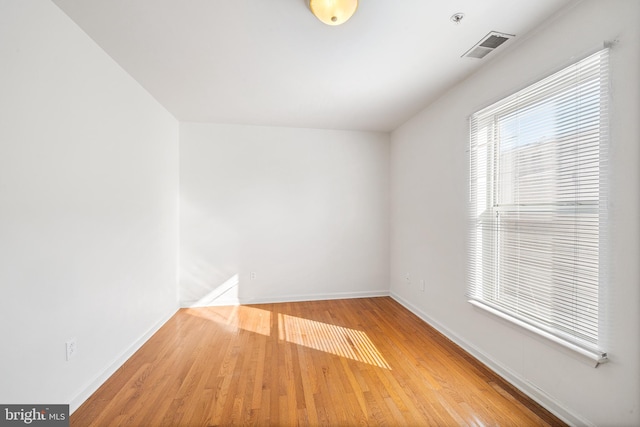 spare room featuring visible vents, baseboards, and wood finished floors