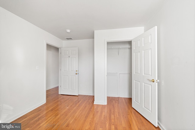 unfurnished bedroom featuring a closet, visible vents, baseboards, and light wood finished floors