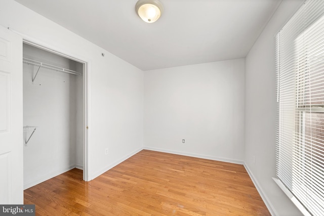 unfurnished bedroom featuring a closet, baseboards, and light wood finished floors