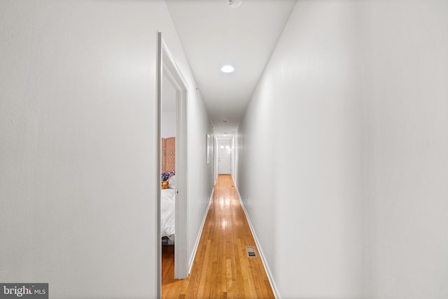 hallway with light wood-type flooring and baseboards