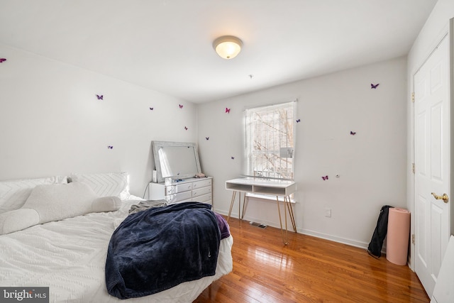 bedroom featuring wood finished floors, visible vents, and baseboards