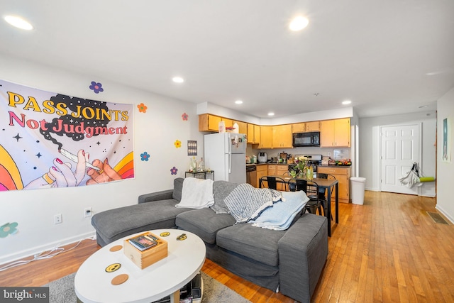 living area with light wood-type flooring, visible vents, baseboards, and recessed lighting