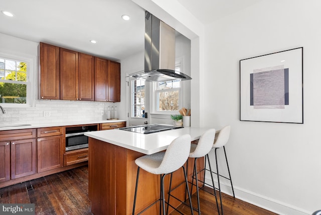 kitchen featuring dark wood finished floors, stovetop, backsplash, and exhaust hood