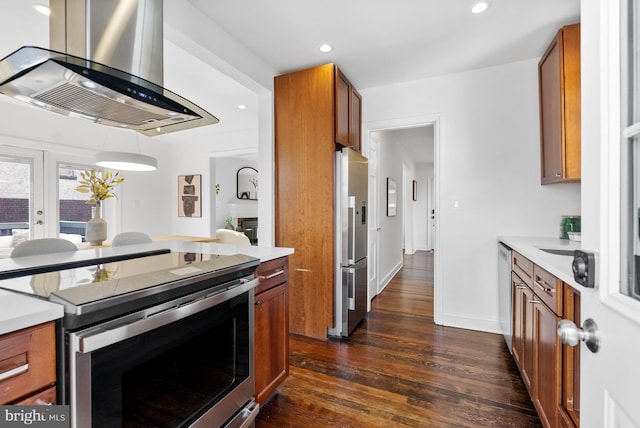 kitchen featuring brown cabinetry, dark wood finished floors, appliances with stainless steel finishes, extractor fan, and light countertops