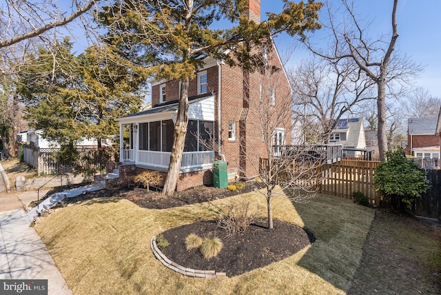 view of front of property featuring a sunroom, fence, and a front lawn