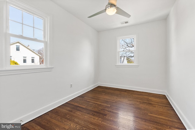 spare room with a ceiling fan, dark wood finished floors, visible vents, and baseboards