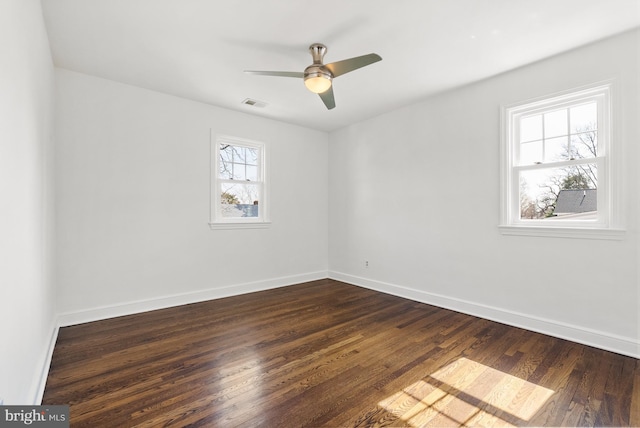 unfurnished room featuring dark wood-style flooring, visible vents, ceiling fan, and baseboards