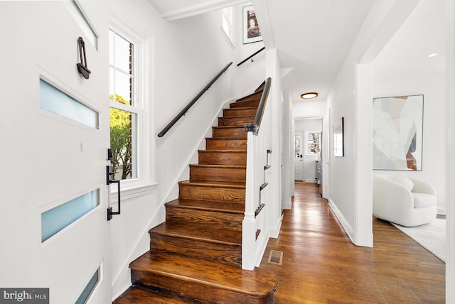 foyer featuring stairs, plenty of natural light, wood finished floors, and visible vents