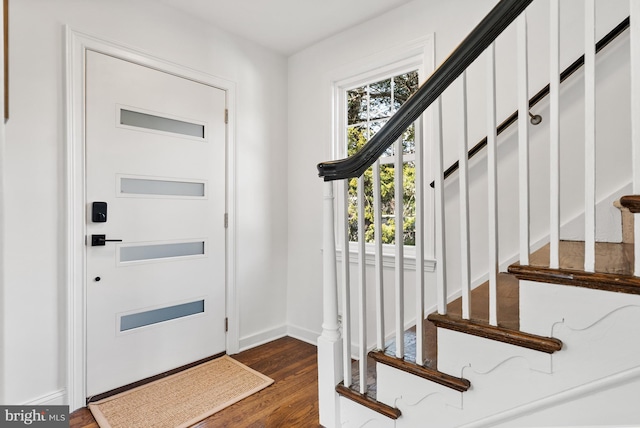 entrance foyer featuring dark wood-type flooring, stairway, and baseboards