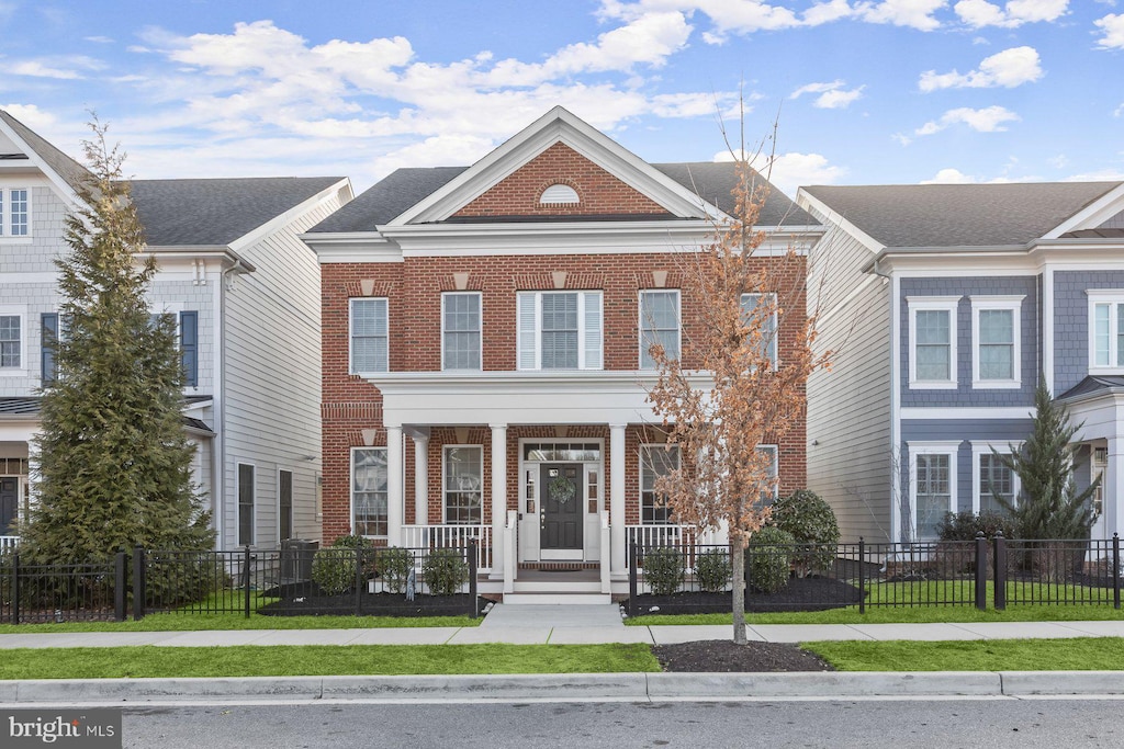 view of front of home featuring a fenced front yard, brick siding, and a porch