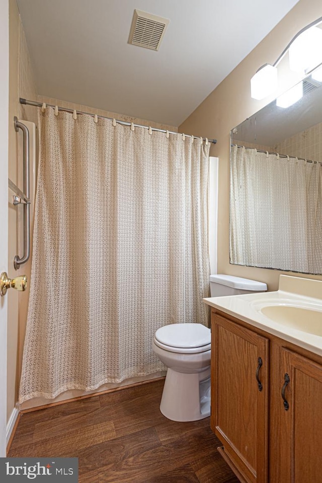 bathroom with toilet, wood finished floors, vanity, visible vents, and a shower with curtain