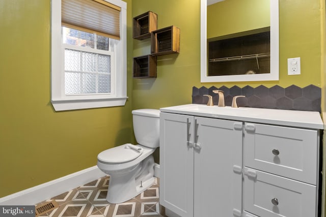 bathroom featuring decorative backsplash, baseboards, vanity, and toilet