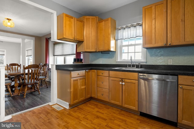 kitchen featuring light wood finished floors, tasteful backsplash, visible vents, stainless steel dishwasher, and a sink