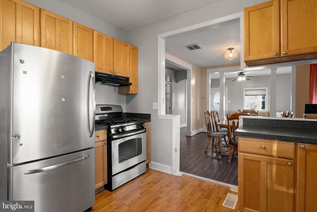 kitchen with light wood finished floors, dark countertops, visible vents, appliances with stainless steel finishes, and under cabinet range hood