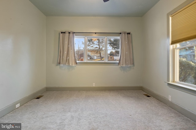 unfurnished room with carpet floors, visible vents, and baseboards