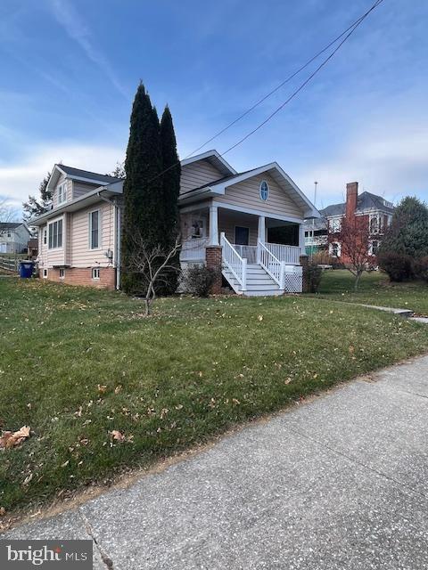 bungalow featuring covered porch and a front yard