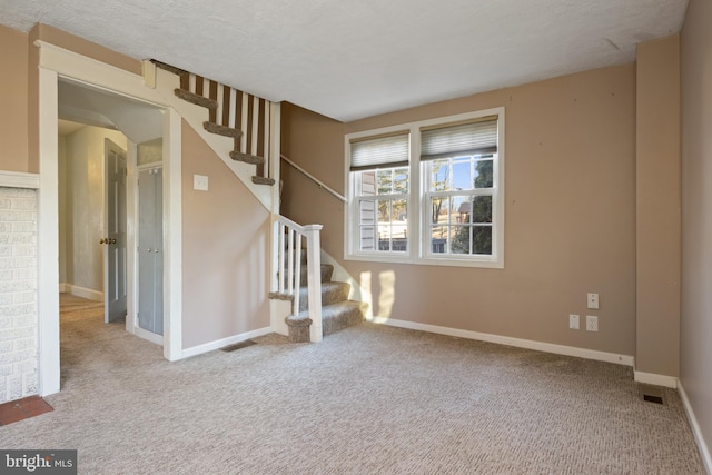 interior space featuring a textured ceiling, stairway, visible vents, and baseboards