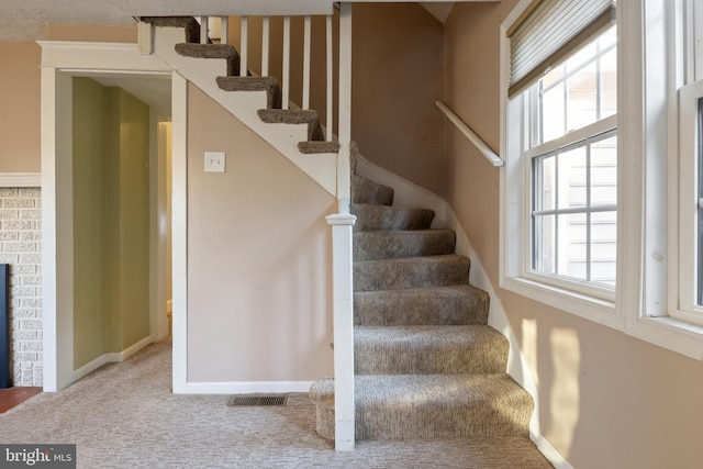 stairway featuring carpet, visible vents, a fireplace, and baseboards