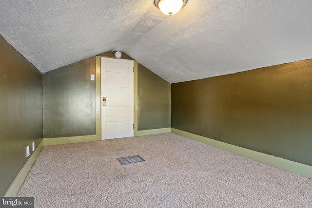 additional living space with a textured ceiling, carpet flooring, lofted ceiling, and baseboards