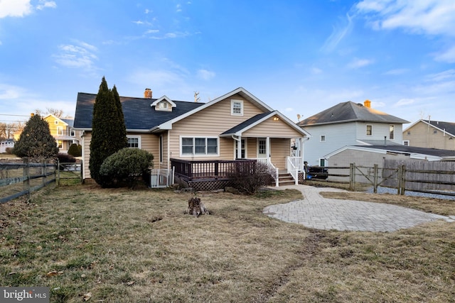 rear view of house with a yard, a porch, a chimney, and a fenced backyard