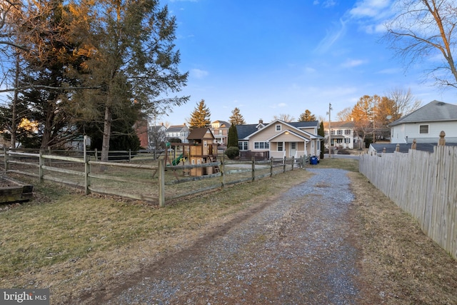 view of road with a residential view and gravel driveway