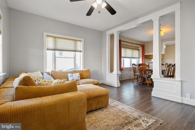 living room featuring dark wood-style floors, decorative columns, baseboards, and ceiling fan