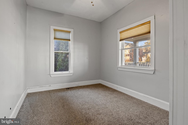 carpeted empty room featuring visible vents and baseboards